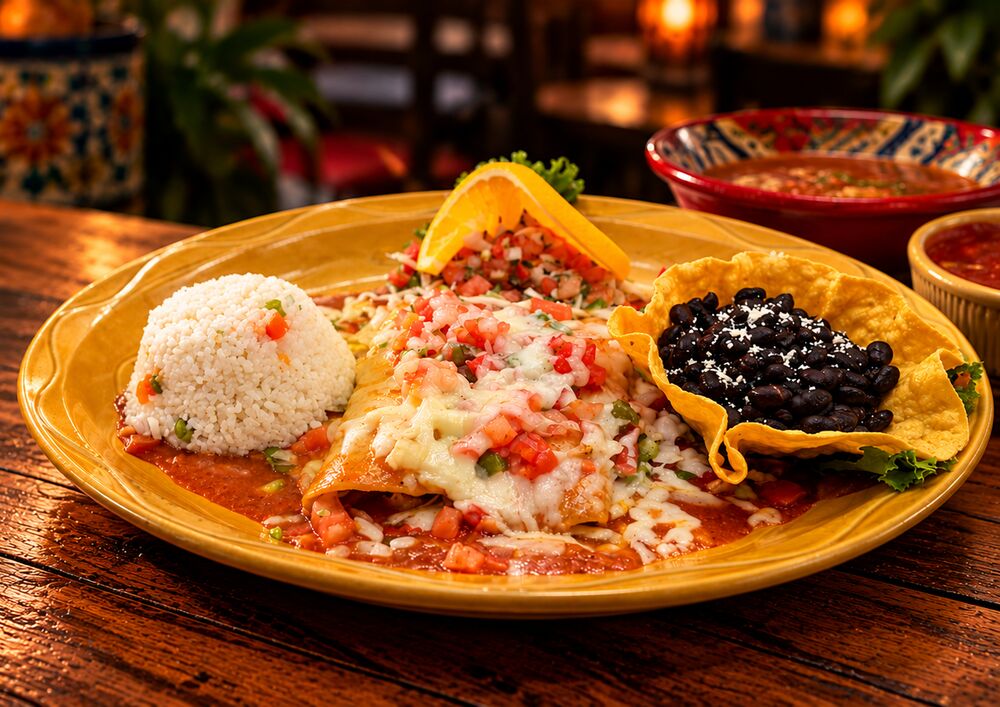 Enchiladas Rancheras topped with melted cheese and pico de gallo, with white rice and black beans in a tortilla bowl