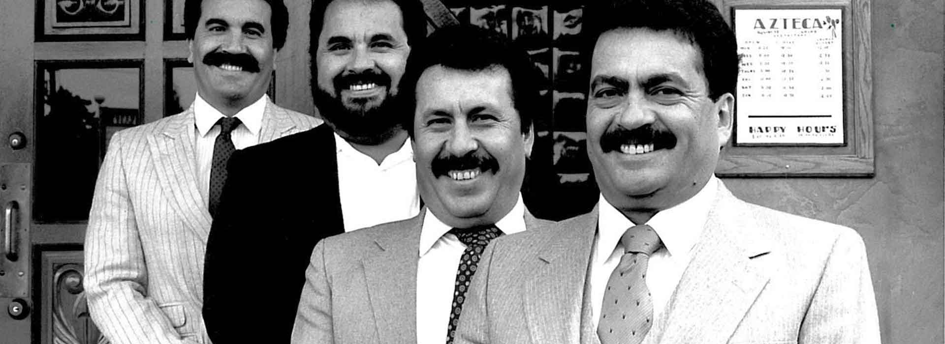 Black-and-white photo of four men in suits standing together in an Azteca restaurant