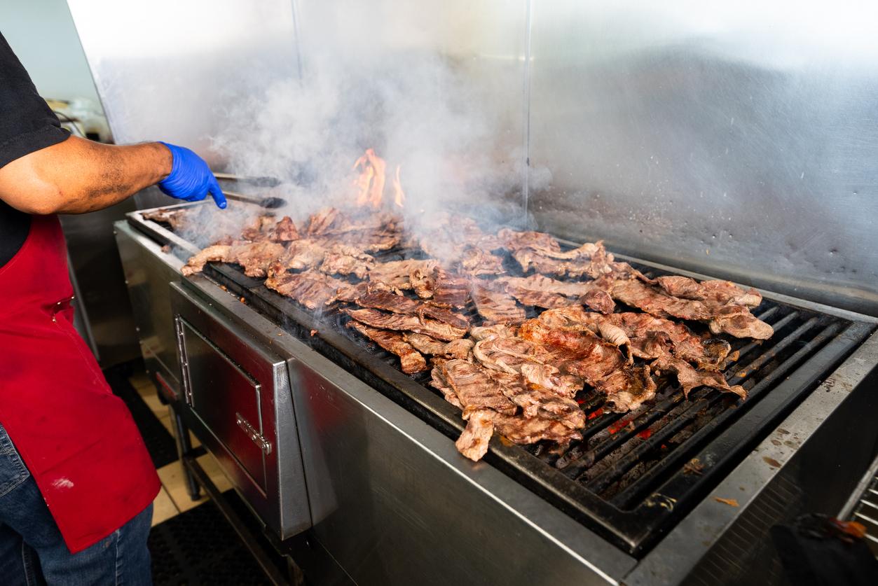 Carne asada cooking on a flaming grill in an Azteca kitchen